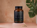 Kiki Health Cognitive supplement bottle on a pink platform with a leafy plant in the background