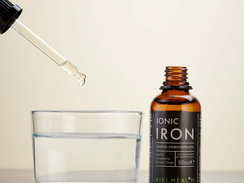 Kiki Health Ionic Iron liquid concentrate bottle with dropper and glass on a light background