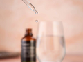 Bottle of serum with dropper and glass container on a blurred background