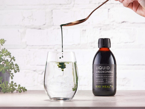 Bottle of Liquid Chlorophyll being poured into a glass with a white brick wall background