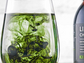 Clear glass with green and black ink swirling inside, next to a bottle of LiChen wine.