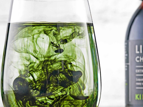 Clear glass with green and black ink swirling inside, next to a bottle of LiChen wine.