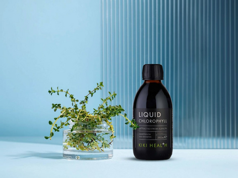 Bottle of KIKI Health Liquid Chlorophyll with a plant on a light blue background