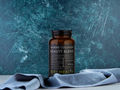 Brown supplement bottle labeled 'Marine Collagen Beauty Blend' by Kiki Health on a blue fabric background.