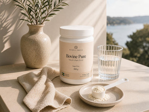 A white tub of Norbre Magnus Bovine Pure supplement powder sits on a beige stone table beside a glass of water, a small dish with a scoop of powder, and a beige vase with greenery, with a blurred outdoor water view in the background.