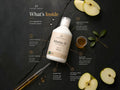 Nordic Omega Marine 15 liquid formula bottle displayed on a dark textured background with ingredient callouts, apple slices, a glass of golden liquid, and a dropper.
