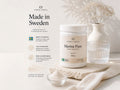 Nordic Omega Marine Pure supplement powder in a white jar, styled on a light beige surface with a small glass dish of powder, a clear glass, and dried flowers in a vase against a soft beige background.