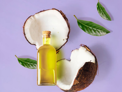 Coconut oil bottle with a split coconut and leaves on a purple background