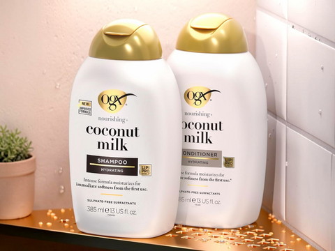 Two bottles of OGX Coconut Milk shampoo and conditioner on a decorative shelf.