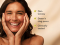Woman with a happy expression touching her face, with text highlighting product benefits on a beige background.