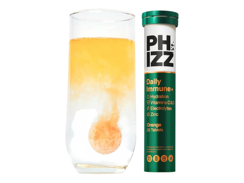 PHIZZ Daily Immune+ supplement tube next to a glass of orange juice on a white background