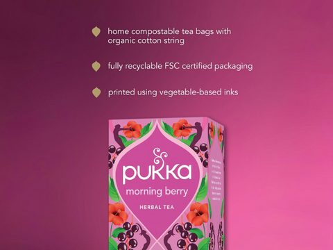 Pukka morning berry herbal tea packaging on a pink background with sustainability information.