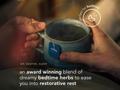 Blue mug held by hands with a tea bag label, text about bedtime herbs, and 'Pukka' branding.
