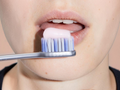 Close-up of a person using a toothbrush with toothpaste on their teeth.