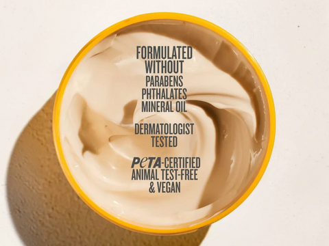 Container of cream with text about product ingredients and certifications on a beige background
