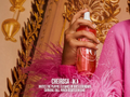 Hand holding a red spray bottle with gold decorative elements in the background