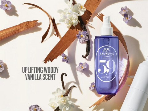Blue bottle with white cap labeled 'SOL DE JANEIRO' surrounded by flowers and vanilla beans on a light background.