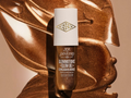 Bronze bottle of Sol de Janerio Glow motions oil on a bronze surface