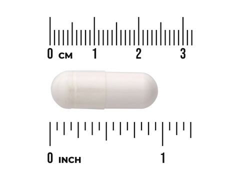 Beige capsule pill with a ruler for scale on a white background