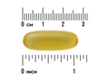 Yellow capsule pill with a ruler for scale on a white background