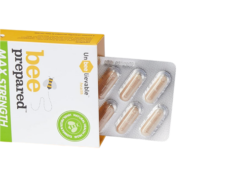Bee Prepared capsule next to a glass of water on a white background.