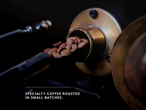 Coffee beans being roasted in a coffee machine with text 'Specialty coffee roasted in small batches'.