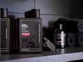 Uppercut Men Detox & Decrease Shampoo bottle on a dark stone surface with a towel and grooming stone in the background.
