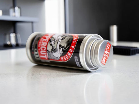 A can of Uppercut Boxing Powder lying on its side on a light gray countertop, with a blurred kitchen or bar background.