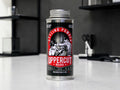 A can of Uppercut Deluxe Styling Powder standing on a light countertop in a modern kitchen or bar setting with dark shelves and bar tools blurred in the background.
