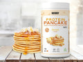 Weider Protein Pancake Mix Banana Flavour 1kg plastic tub with a stack of golden banana protein pancakes with syrup drizzle.