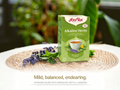 Yogi Tea Alkaline Herbs packaging on a table with a blurred green background
