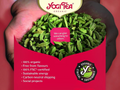 Yogi Tea organic green tea leaves held in a hand with brand logo and sustainability information.