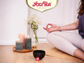 Person meditating with Yogi Tea products on a wooden floor