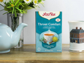 Yogi Tea Throat Comfort box on a wooden surface with a teapot and mug in the background.
