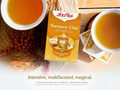 Yogi Tea Turmeric Chai package with two cups of tea and tea bags on a wooden surface.